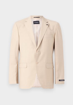 Beige zakó struktúrált anyagból, két gombbal, mellzsebbel és két elülső zsebbel. Címkézett belső béléssel rendelkezik.