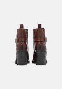 Bottes chevilles en cuir marron avec une finition texturée, dotées d'une fermeture éclair, d'accents bordeaux contrastants et d'un solide talon bloc.