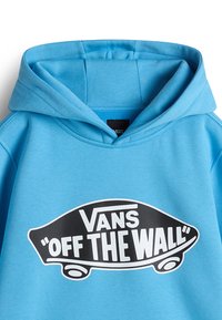 Světle modrá mikina s kapucí vyrobená z měkké látky, s velkým černobílým grafickým motivem "Vans Off the Wall" ve tvaru skateboardu na přední straně.