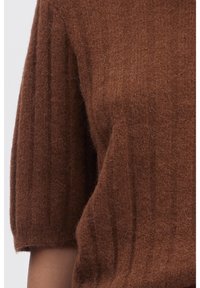 Pull en tricot marron à manches courtes, avec une texture côtelée et une finition douce et duveteuse. Le tissu semble chaud et léger.