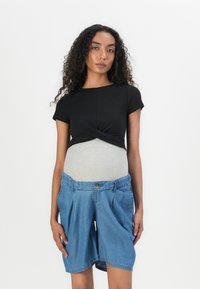 Svart t-skjorte med kort erm og vridd frontdesign, kombinert med lyseblå denimshorts med knappeåpning og sidelommer.
