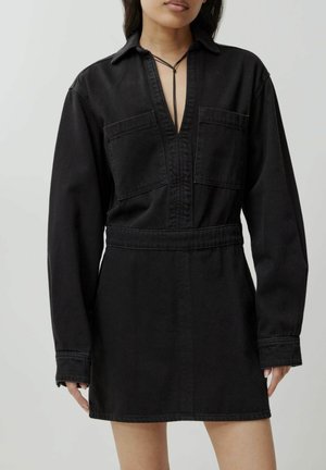 Zwarte denim jurk met lange mouwen, kraag en twee borstzakken. Kenmerkt zich door een diepe V-hals en een getailleerde taille voor een gestructureerde pasvorm.