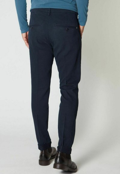 Chinos blu scuro con una vestibilità slim, gambe affusolate e due tasche posteriori. Realizzati in morbido tessuto di cotone. Scarpe marroni completano il look.
