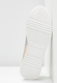 Semelle d'une basket blanche avec des crampons texturés, nom de la marque "CAFèNOIR," et taille 37 visibles.