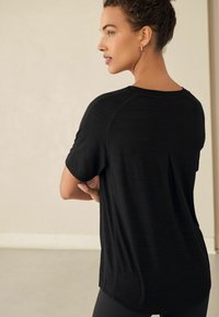 Zwarte t-shirt met korte mouwen en een relaxte pasvorm, met een plooidetail aan de achterkant, gemaakt van een textuurstof en met een ronde hals.