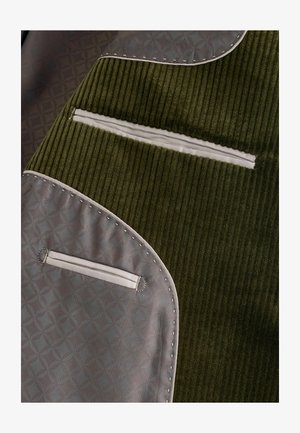 A green corduroy fabric combined with gray patterned material features several zippered pockets and decorative stitching along the edges.