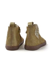 Stivaletti alla caviglia in suede marrone con un accento a forma di cuore glitterato, punta rotonda, cerniera posteriore e linguetta per la calzata. Suola piana in gomma con grip testurizzato.