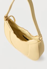 Sac à main en similicuir jaune avec une texture lisse, fermeture éclair et une anse courte ; présente un design simple et courbé ainsi qu'une étiquette interne.