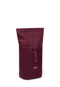 Sac à dos haut, bordeaux avec rabat enroulé, doté d'une sangle à boucle à l'avant et d'une petite étiquette "Larkson Hamburg" en bas à l'avant.