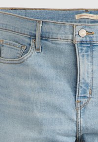 Τζιν παντελόνι από ανοιχτό μπλε ντένιμ με στενή εφαρμογή, σχεδιασμό με πέντε τσέπες, ορατές ραφές και ετικέτα με λογότυπο στη μέση.