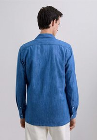Camisa de denim azul medio con mangas largas, puños de botón y un cuello clásico. Presenta un yugo trasero recto y un corte relajado.
