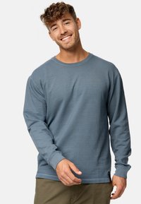 Langärmliges Shirt mit Rundhalsausschnitt aus strukturiertem blauen Stoff, mit gerippten Bündchen und einem kleinen Logoetikett am Saum.