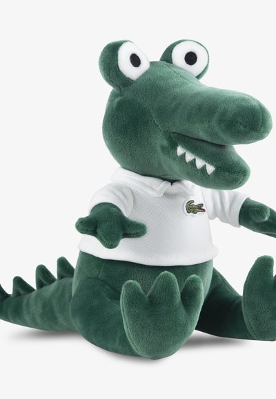 Мека плюшена играчка крокодил в зелено с бяла поло риза с бродиран логотип Lacoste, кръгли очи и текстурирана кожа, седящ с протегнати ръце.
