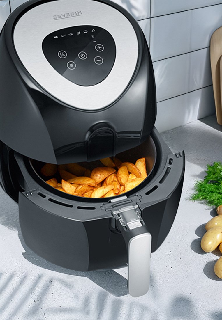 Schwarze Heißluftfritteuse mit einer Edelstahlplatte, digitalem Bedienfeld und einem Korb voller goldbrauner Kartoffelspalten.