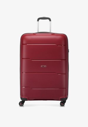 Maleta rígida roja con surcos horizontales, mango telescópico plateado, cuatro ruedas giratorias negras y cierre de cremallera a lo largo del borde.