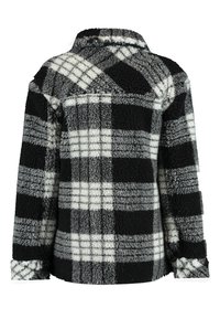 Chaqueta de forro polar a cuadros en blanco y negro con un tacto texturizado similar a la lana, que presenta un cuello con solapa y mangas largas.