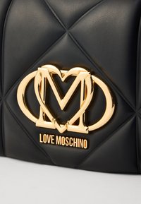 Borsa a mano in pelle sintetica nera trapuntata con logo e dettagli metallici dorati Love Moschino. Presenta un motivo a diamante sulla superficie.