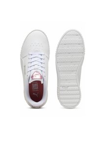 Scarpe da ginnastica bianche con suole piatte, suole in gomma testurizzata e design con lacci. Presentano una patch con logo rosa sulla linguetta e fori sulla punta.