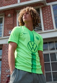Maglietta da calcio verde brillante con striscia verticale verde scuro, logo VW sul davanti, maniche corte e design a V.