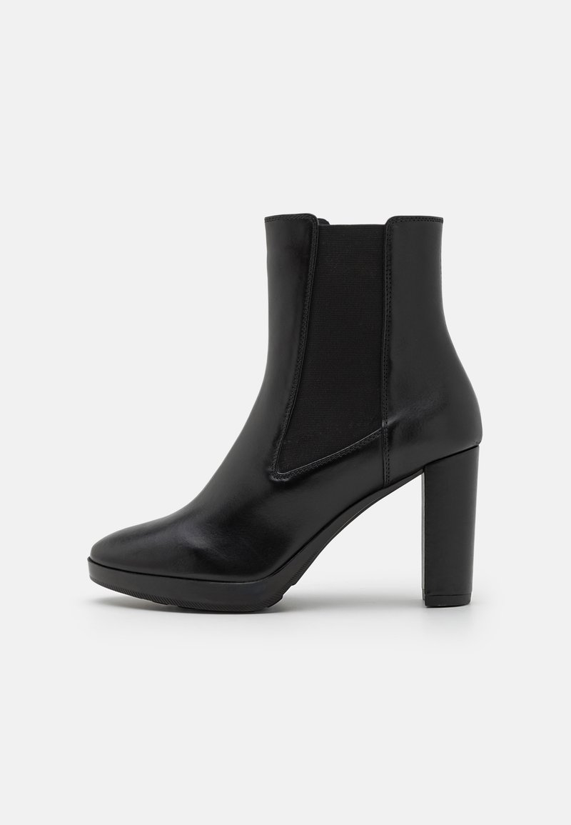 Bota de tornozelo em couro preto com um salto robusto, apresentando painéis laterais elásticos e um acabamento suave e brilhante. Bico arredondado com um design minimalista.