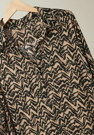 Camicia a maniche lunghe con motivo zigzag nero e beige, colletto e patta con bottoni, realizzata in un materiale morbido e testurizzato.