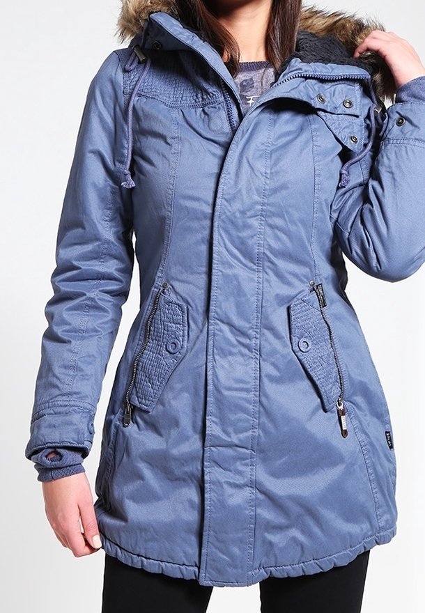 Blå isolerad parkas med huva, fuskpälsdetaljer, dragkedjefickor och ett quiltat mönster. Utrustad med snörjusteringar och en medellång längd.