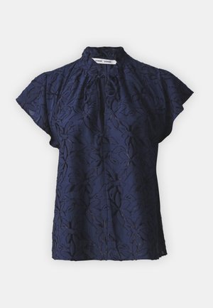 Blusa blu navy con maniche corte a campana, caratterizzata da un sottile motivo floreale in rilievo e un dettaglio di scollatura arricciata.