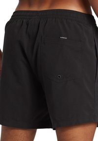 Bañador negro de tejido ligero, con cintura elástica, bolsillos laterales y un bolsillo trasero con parche y detalle de ojal.