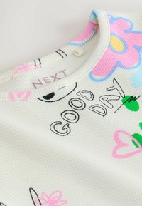 Top din material alb nervurat cu modele florale colorate și textul „GOOD DAY” în negru. Accentuate cu desene roz, albastre și verzi.