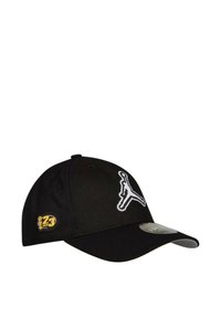 Gorra de béisbol negra hecha de tela con visera curva. Presenta un logotipo blanco de Jordan en la parte frontal y una insignia amarilla con el número "23" en el costado.