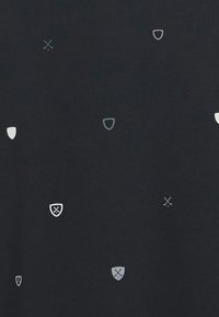 Tissu noir avec un motif répétitif de divers boucliers de couleur claire et des épées croisées dans des nuances de gris et blanc. Texture lisse.