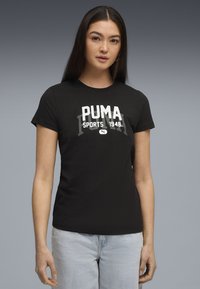 Sort T-shirt med korte ærmer, med hvid "PUMA SPORTS 1948" grafik på forsiden. Fremstillet af bomuld, tætsiddende design med rund hals.
