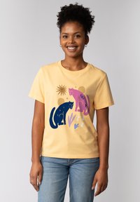 Gele katoenen t-shirt met een grafisch ontwerp van een zwarte en roze panter tussen abstracte vormen en lijnen. Korte mouwen en ronde hals.