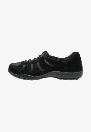 Czarny niskoprofilowy sneaker z przednią sznurowadłą, teksturowaną podeszwą i miękką cholewką z tkaniny z subtelnym logo marki po boku.