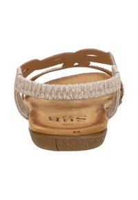 Beige sandaal met een gestructureerde band, ingewikkeld uitsnijdontwerp, platte zool en een gevoerde voetbed; heeft een decoratieve accent aan de zijkant.