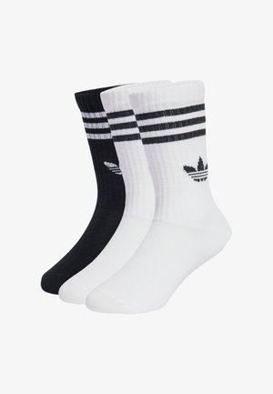 Tri parova čarapa u crnoj i bijeloj boji, s dvjema crnim prugama na vrhu i logotipom na svakoj čarapi. Izrađene su od teksturirane tkanine.