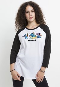 Hvid raglan t-shirt med sorte ærmer. Har farverige tegneseriefigurer og teksten "#weekend" trykt på brystet. Blødt bomuldsmateriale.