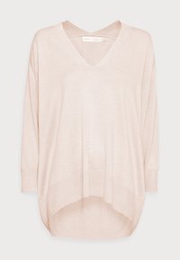 Ljust beige V-ringad oversized långärmad tröja med nedhasade axlar och ribbade muddar och avslut, designad med en asymmetrisk nederkant.