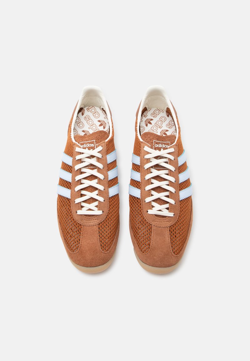 Paire de baskets Adidas marron avec des bandes bleu clair, des lacets blancs et des semelles intérieures de marque, vues de dessus sur un fond blanc.
