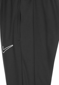 Pantaloni sportivi neri in tessuto liscio con un pannello in rete, con il logo Nike bianco sul lato sinistro. Include un elastico in vita.