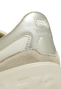 Sneaker caratterizzata da una combinazione di suede grigio e pelle metallizzata argento, con tacco testurizzato e dettaglio del logo impressato.