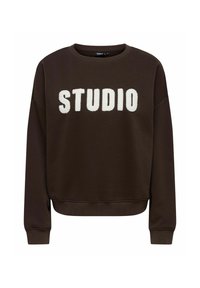 Bruine sweatshirt met een ronde halslijn en geribbelde manchetten, met grote, witte pluizige letters die "STUDIO" op de voorkant spellen.