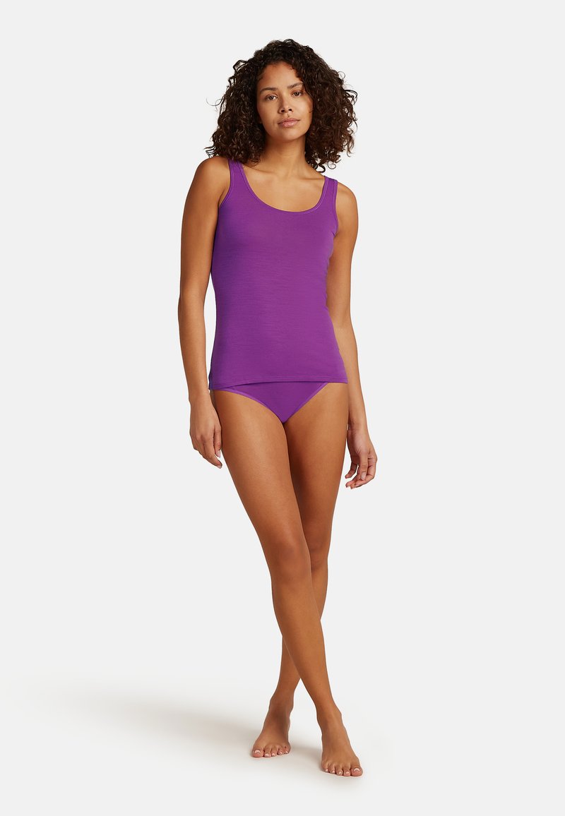 Top in cotone viola e bikini coordinato, texture liscia, design semplice, taglio aderente, senza maniche. Modella in piedi a piedi nudi, braccia rilassate.