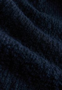 Granatowy, dzianinowy materiał z teksturowanym, prążkowanym wzorem, ukazujący miękki, gruby i puszysty wygląd.