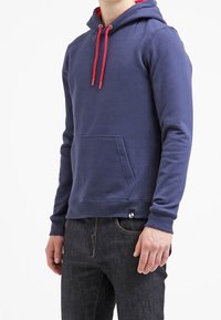 Felpa blu navy con cordino rosso, tasca frontale e tessuto morbido; presenta un piccolo logo sull'orlo sinistro inferiore.