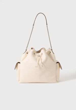 Sac d'épaule matelassé en cuir crème avec fermeture à cordon, bandoulière chaîne en métal et poches latérales sur fond uni.