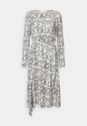 Svart-hvitt mønstrete kjole med lange ermer, rund hals, elastisk midje og en flytende skjørt som strekker seg nedenfor kneet.