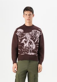 Suéter marrón de punto que presenta un diseño de escena del oeste en rosa claro, con un vaquero montando un caballo, y con cuello y puños acanalados.