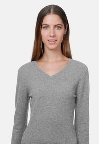 Pull gris à manches longues avec un design en V. Texture douce et coupe ajustée, avec des accents côtelés au niveau de l'encolure et des poignets.
