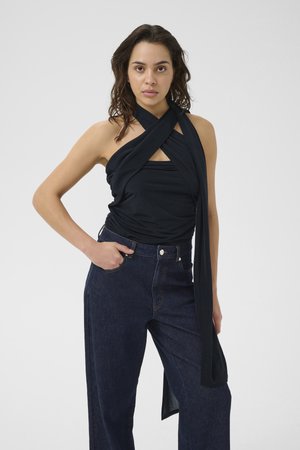 Sort kryds-band top lavet af blødt stof, parret med højtaljede mørke denim jeans, med lige ben og frontlommer.